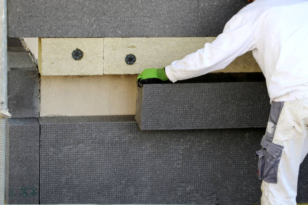Construction workers insulating house external wall